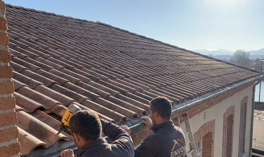 Pan de toiture en tuiles canal à Muret pendant la pose d'une gouttière par les couvreurs d'Envol Couverture